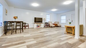 A spacious living room with a wooden floor, a TV, a fireplace, and a dining area with chairs and a table. - Ludlow Townhome: 3 Mi to Okemo Mountain! (Ludlow)