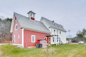 A red and white house with a small shed and a staircase leading to a porch.