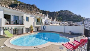 A rooftop pool with a clear view of the surrounding buildings and a hillside.