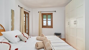 A bedroom with a bed, pillows, a window, and a wardrobe.