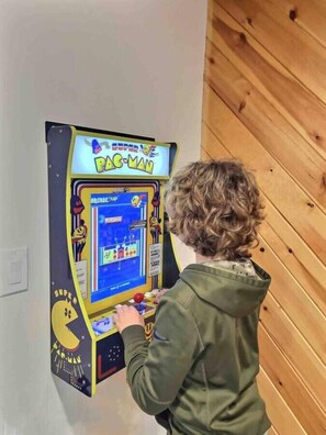 Niño jugando a Pac-Man en una máquina arcade.