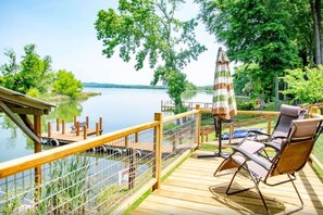 Un pontile in legno con vista su un lago, una sedia a sdraio e un ombrellone.