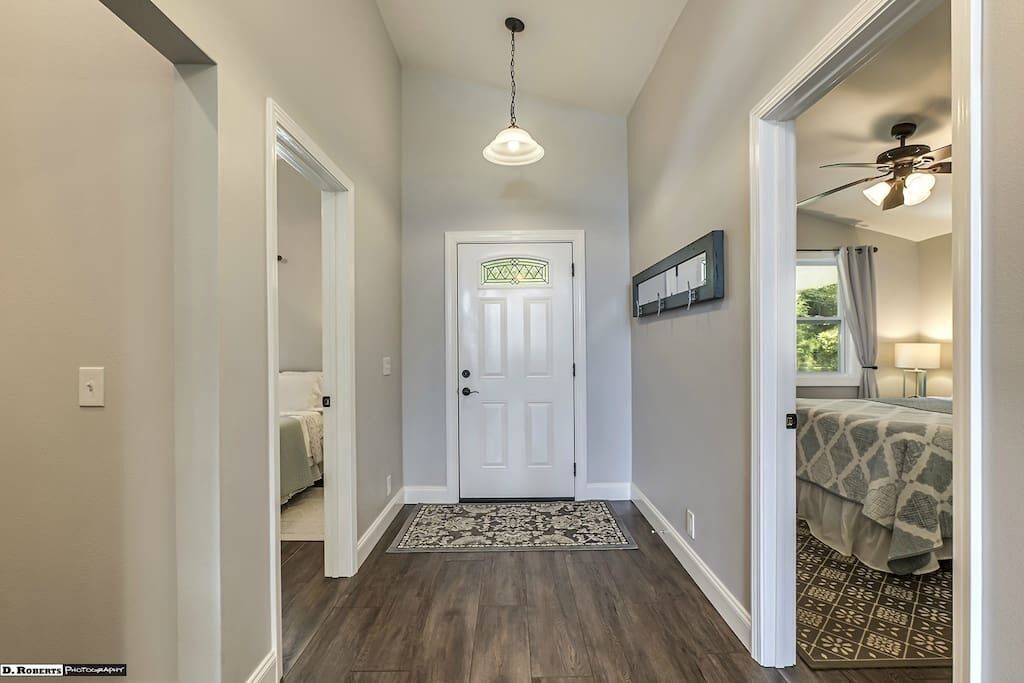 A hallway with a white door, a patterned rug, and a ceiling fan.