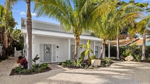 Un edificio blanco con el número '3010' en la fachada, rodeado de palmeras y un jardín ajardinado.