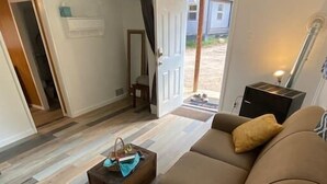 Un salon avec un canapé marron, une petite table basse en bois et une porte donnant sur l’extérieur.
