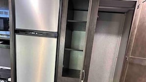 A walk-in closet with a mirrored wardrobe, open shelving, and drawers.