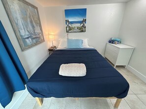 Ein Schlafzimmer mit Bett, Nachttisch, Kommode, einem Gemälde und einer Lampe.