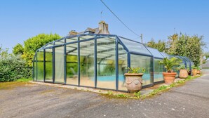 A greenhouse with a curved roof, large windows, and potted plants along the side. - Holiday Home 'Maison 6 Personnes Avec Piscine' with Private Pool and Wi-Fi (Le conquet)