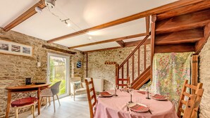 A dining area with a wooden table set for four, stone walls, and a staircase. - Holiday Home 'Maison 6 Personnes Avec Piscine' with Private Pool and Wi-Fi (Le conquet)