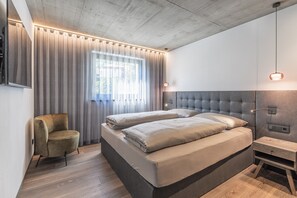 Une chambre moderne avec un grand lit, une chaise et une table de chevet.