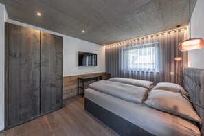 A modern bedroom with a large bed, a TV mounted on the wall, and a wooden wardrobe. - Apartment 'Köfele Lodge Sepp' with Mountain View, Shared Pool and Wi-Fi (Partschins)