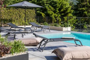 A poolside area with lounge chairs, a pool, and a hedge. - Apartment 'Köfele Lodge Sepp' with Mountain View, Shared Pool and Wi-Fi (Partschins)