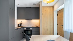 Une cuisine moderne avec des meubles gris, une porte en bois et une table à manger agrémentée d’un set de table noir.