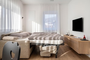 Une chambre à coucher moderne avec un lit, un bureau, une chaise et un téléviseur.