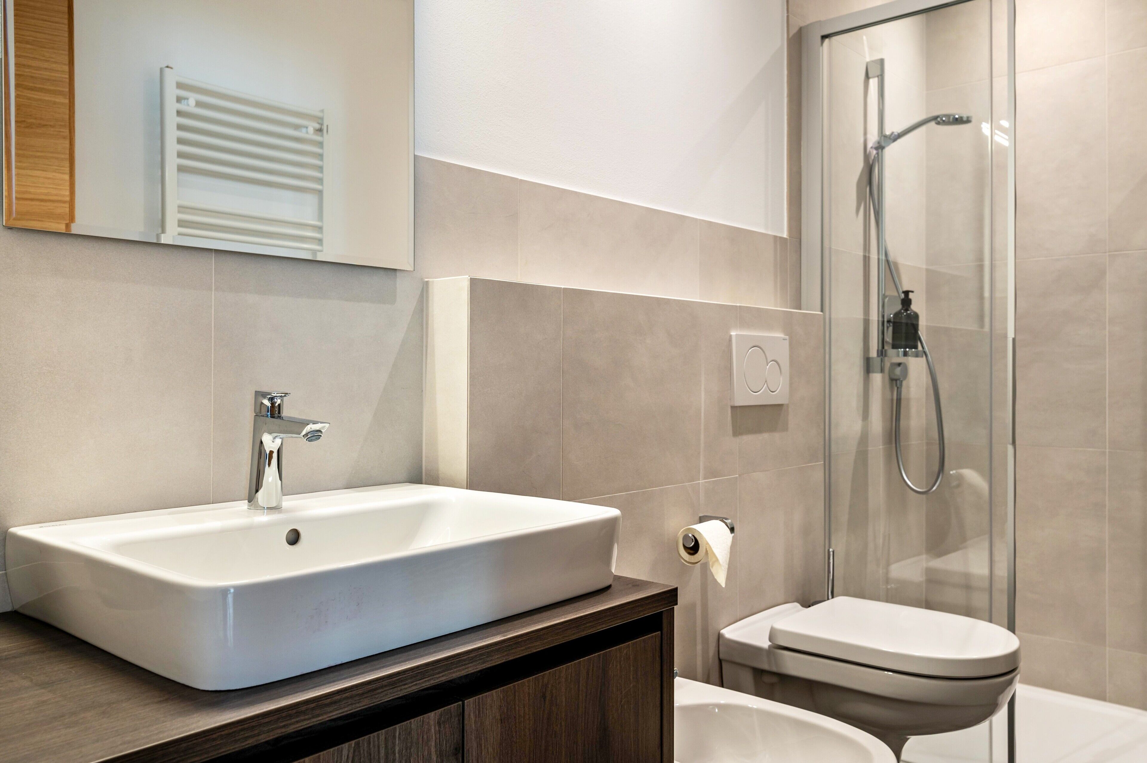 Une salle de bain moderne avec un grand lavabo blanc, des toilettes et une douche à parois de verre.