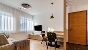 Un salon moderne comprenant un canapé, une table à manger, des chaises, un téléviseur et une porte en bois.