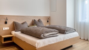 Une chambre à coucher moderne avec une tête de lit en bois, un lit agrémenté de plusieurs oreillers, des lampes de chevet et une table de chevet.