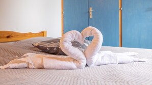 A bed with a towel arranged in a heart shape, a patterned pillow, and a blue wardrobe in the background. - Apartment 'Appartement Spacieux 6 Personnes' with Mountain View, Private Terrace and Wi-Fi (LE GRAND BORNAND)