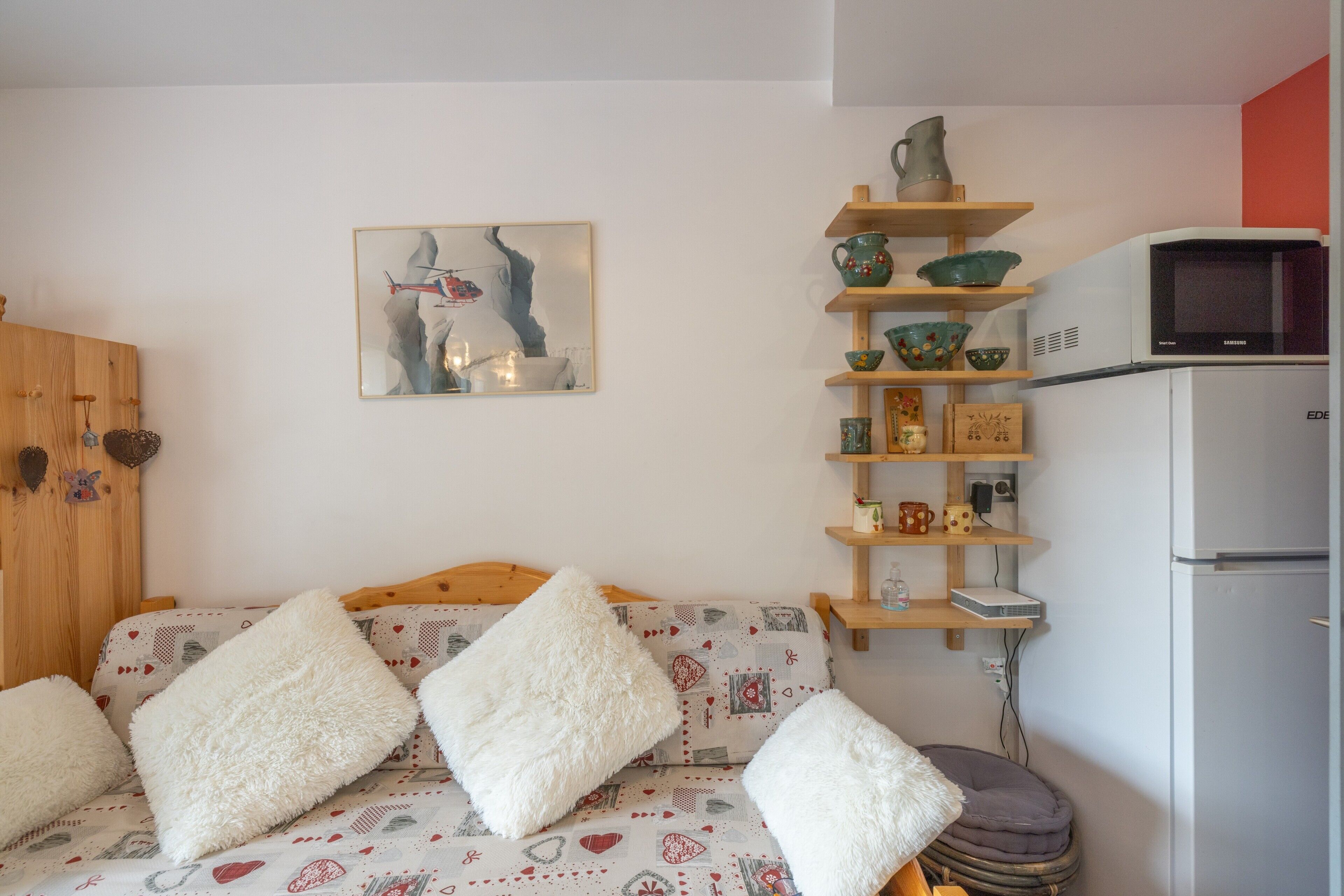 Ein gemütliches Zimmer mit einem Bett, einem Regal mit Küchenutensilien, einer Mikrowelle und einem Kühlschrank.