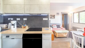 A modern kitchen with a built-in dishwasher, a coffee maker, and a small dining area with a table and chairs. - Apartment 'Appartement Spacieux 6 Personnes' with Mountain View, Private Terrace and Wi-Fi (LE GRAND BORNAND)
