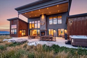 A modern two-story house with a fireplace, outdoor seating, and a hot tub.