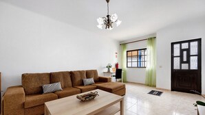 A living room with a sofa, a coffee table, a chandelier, a door, and a window with curtains. - Holiday Home 'Brita' with Private Terrace, Balcony and Wi-Fi (Raposeira)
