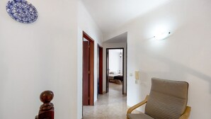 A hallway with a chair, a wooden sculpture, and a door leading to a bedroom. - Holiday Home 'Brita' with Private Terrace, Balcony and Wi-Fi (Raposeira)