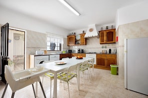 A kitchen with a dining table, chairs, a baby high chair, and a washing machine. - Holiday Home 'Brita' with Private Terrace, Balcony and Wi-Fi (Raposeira)