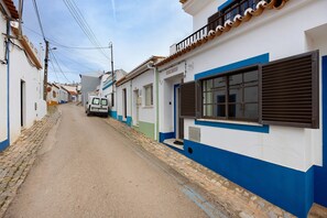 A narrow street lined with white buildings with blue trim and a white van parked on the side. - Holiday Home 'Brita' with Private Terrace, Balcony and Wi-Fi (Raposeira)