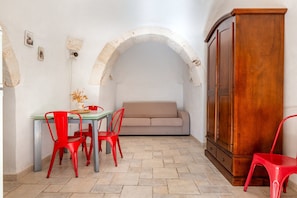 A room with a dining table, red chairs, a sofa, and a wooden cabinet.