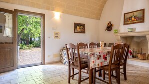 Un coin repas avec une table dressée pour quatre personnes, une cheminée et une vue sur l’extérieur, accessible par une porte vitrée.