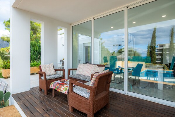 A modern outdoor seating area with wicker furniture and a glass wall.