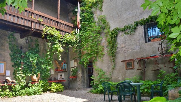 A courtyard with a wooden bridge, green chairs, and a gravel path.