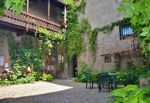 Un patio con un puente de madera, sillas verdes y un camino de grava.