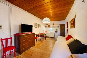 A cozy room with a wooden ceiling, a television on a dresser, a dining table with chairs, and a sofa with pillows. - Apartment 'Cascina Des Religieuses - Tilleul' with Mountain View, Private Terrace and Wi-Fi (Sarre)