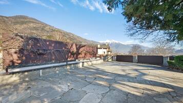 A paved courtyard with stone tiles, a metal fence, and a building with a flat roof.
