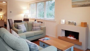 A living room with a sofa, armchair, and a fireplace. - Leven Lodge 3 - UK46045 (Loch Lomond)