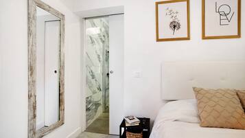 Un dormitorio con una cama, una mesita de noche, un espejo y dos cuadros en la pared.