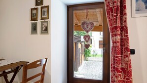 A wooden door with heart-shaped decorations, a table with a lace tablecloth, and framed pictures on the wall.
