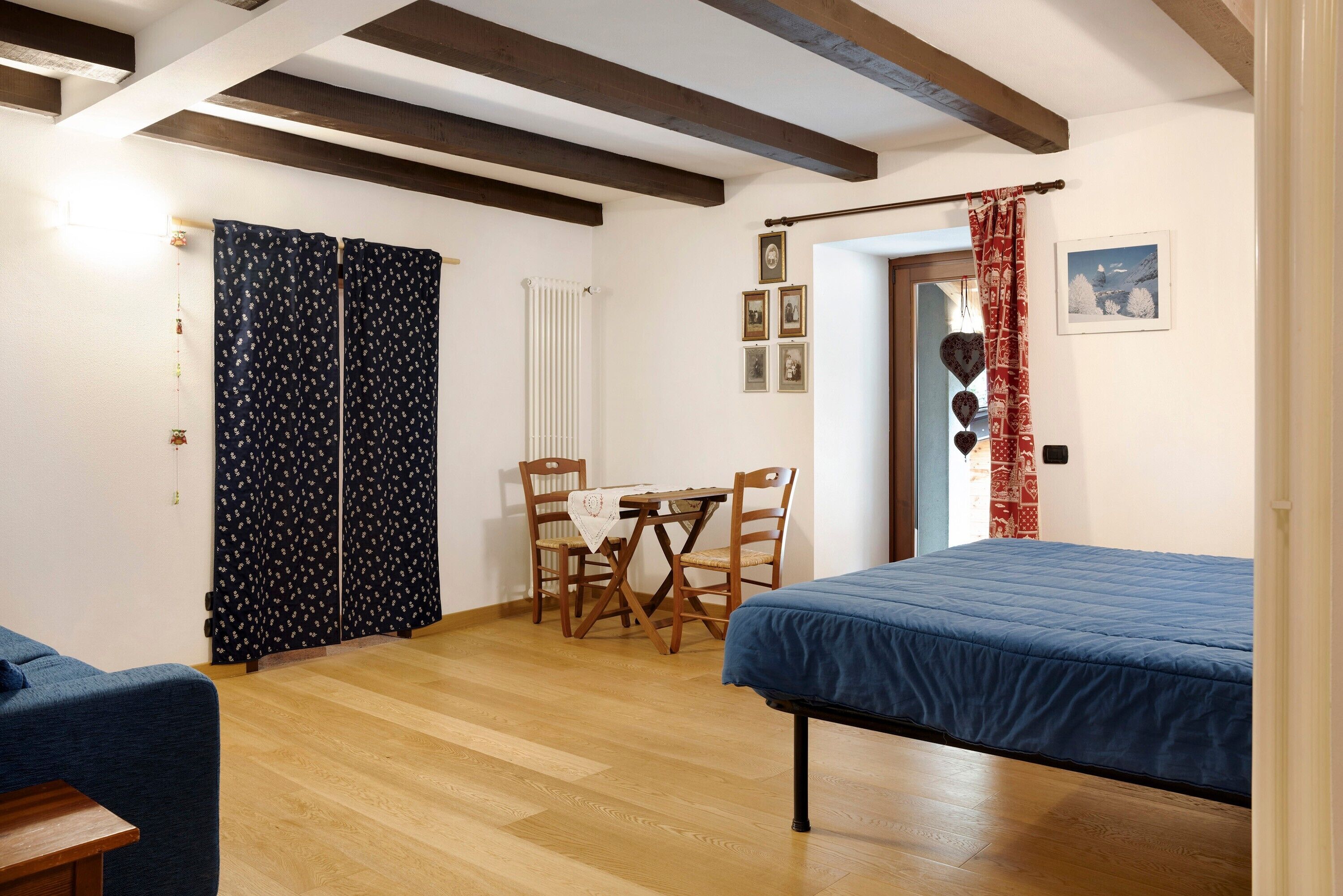 Une pièce comprenant un lit, une table avec des chaises, un radiateur et une porte avec des rideaux.