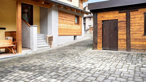 A cobblestone street with wooden buildings, a bench, and a staircase.
