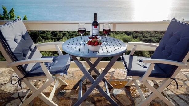 A round table with two chairs, a bottle of wine, two glasses, and a bowl of strawberries on a terrace overlooking the sea. - Idyllic Sunsets Seaviews Pool - Villa Melina (Lefkada)