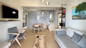 A modern living room with a sofa, coffee table, and TV. There is a staircase leading to another level. - Idyllic Sunsets Seaviews Pool - Villa Melina (Lefkada)