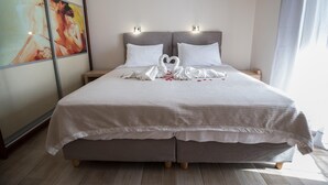 A double bed with a heart-shaped towel arrangement, a nightstand, and a painting on the wall. - Idyllic Sunsets Seaviews Pool - Villa Melina (Lefkada)
