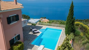 A swimming pool with a stone deck, a lounge area with chairs, and a view of the sea. - Idyllic Sunsets Seaviews Pool - Villa Melina (Lefkada)