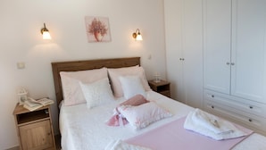 A neatly made bed with pillows and a blanket, a bedside table with a book and a lamp, and a wardrobe with a mirror. - Stunning Seaviews Pool Beach - Pasithea (Lefkada)