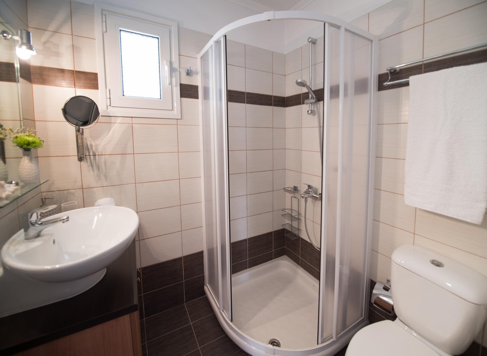 A modern bathroom with a glass-enclosed shower, a white sink, and a toilet.