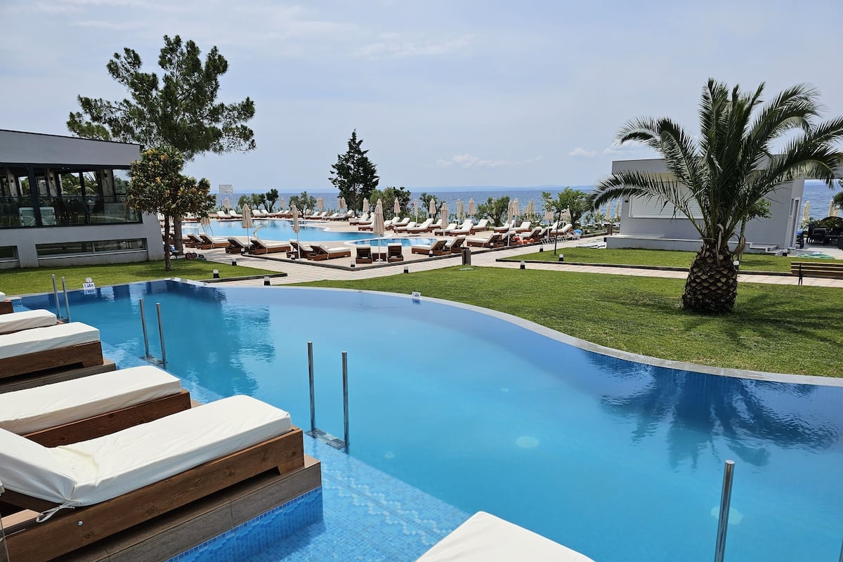 A swimming pool with lounge chairs and a view of the ocean.