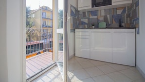 A modern kitchen with white cabinets, a microwave, and a tiled backsplash. - Athena Affittacamere (Bologna)