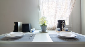 A dining table with two white plates, a potted plant, and a coffee maker. - Athena Affittacamere (Bologna)